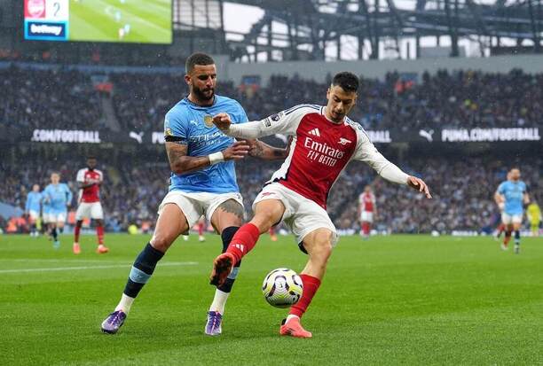 Kyle Walker (vlevo) bojuje o míč s Gabrielem Martinellim z Arsenalu
