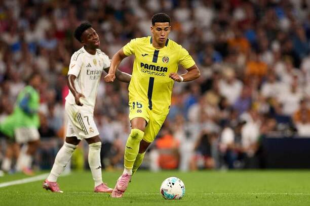 Santiago Mouriño z&nbsp;Villarrealu běží s&nbsp;míčem. V pozadí je Vinícius Jr. hájící barvy Realu Madrid